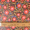 Tissu imperméable Beyoncé type ciré de pluie motif fleurs rouges fond cacao